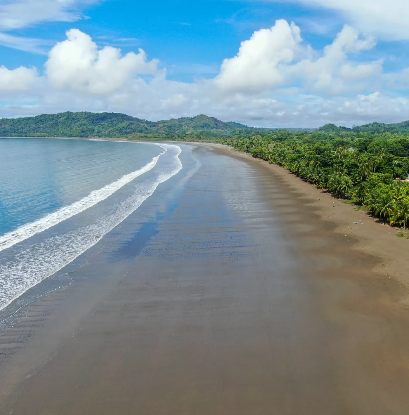 Aerial view of the long beach at Playa Hermosa, Guanacaste, backed by forest