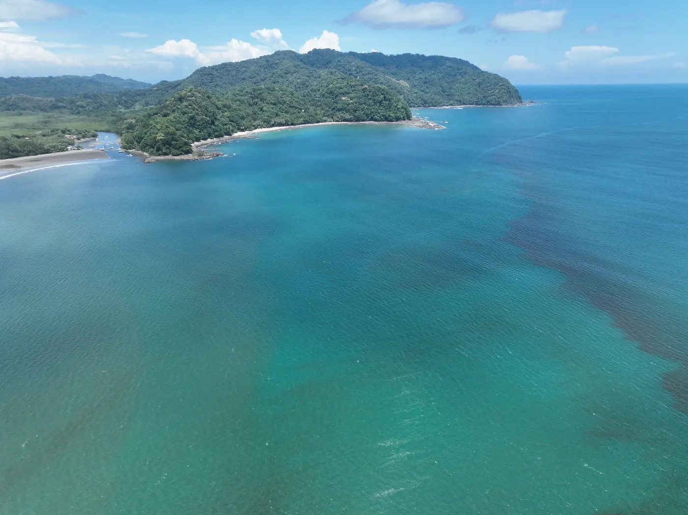 Aerial view of turquoise water and green hills along the coast at Playa Ocotal